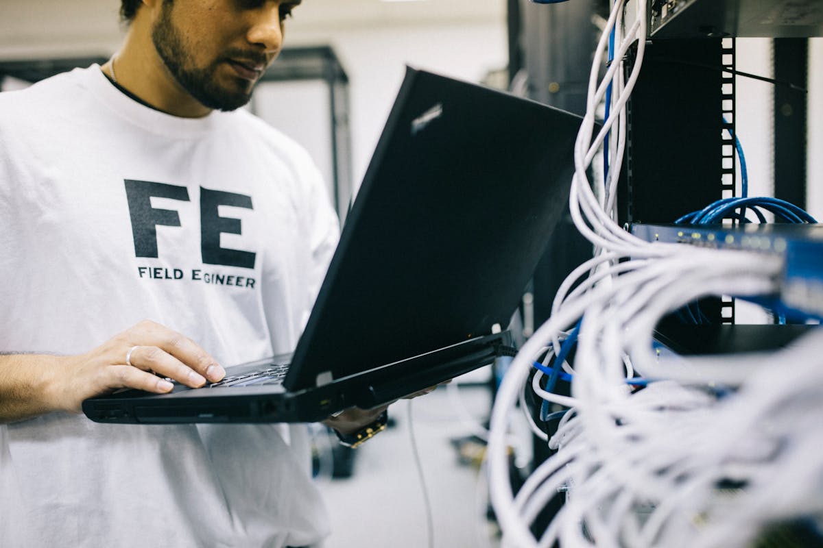 Tecnico di campo con laptop accanto a un armadio di rete