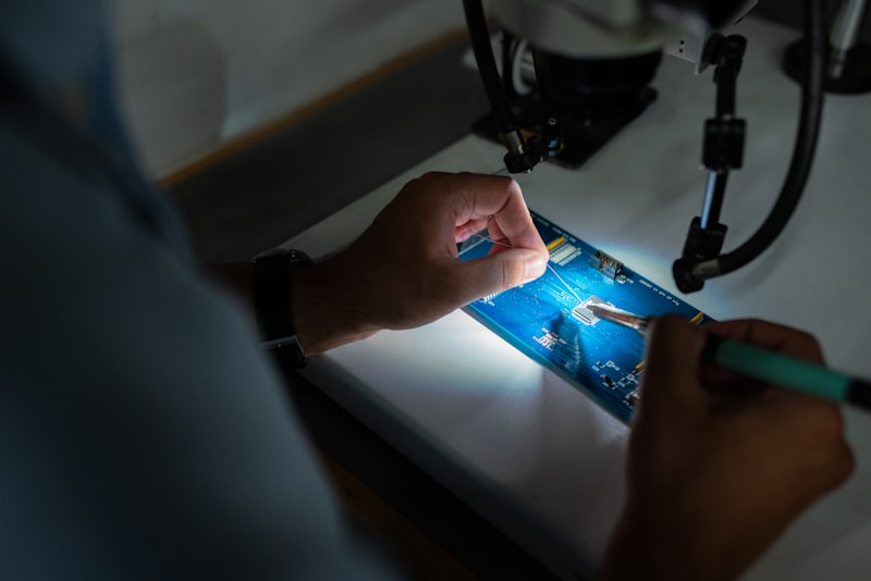 Tecnico al microscopio su scheda elettronica